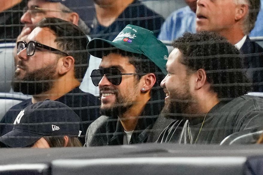 Bad Bunny, center, watches play between the New York Yankees and the Toronto Blue Jays during the second inning of Game 3 of baseball's American League Division Series, Tuesday, Oct. 7, 2025, in New York. (AP Photo/Yuki Iwamura)