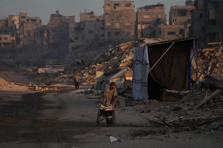 Palestinians walk trough the destruction caused by the Israeli air and ground offensive in Sheikh Radwan neighborhood in Gaza City, Wednesday, Oct. 22, 2025. (AP Photo/Abdel Kareem Hana)