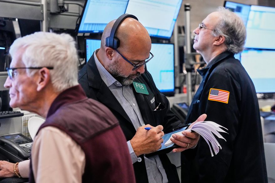 Options trader Steven Rodriguez, center, works on the floor of the New York Stock Exchange, Monday, Oct. 20, 2025. (AP Photo/Richard Drew)