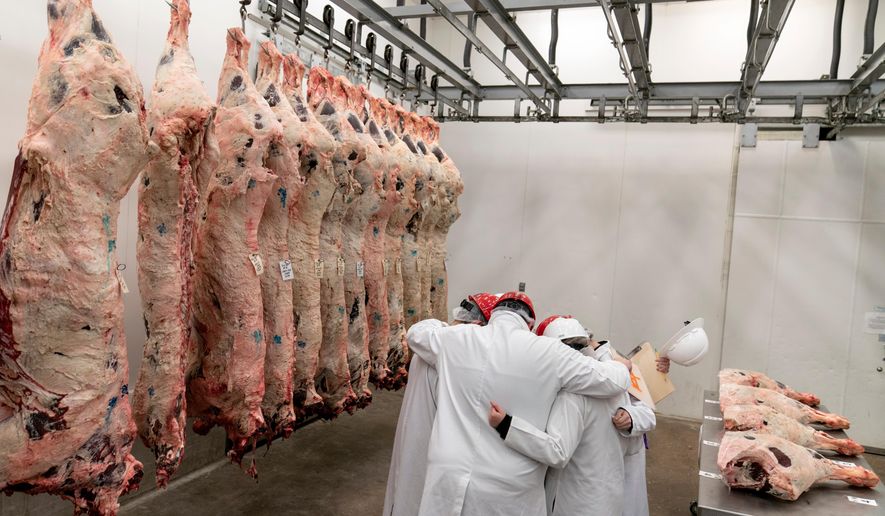 Team leader Kevin Eschberger, center, huddles his team in prayer next to half cows hanging in a freezer at the conclusion of a youth meat judging competition at Texas A&M University in College Station, Texas, on April 22, 2023. (AP Photo/David Goldman) **FILE**