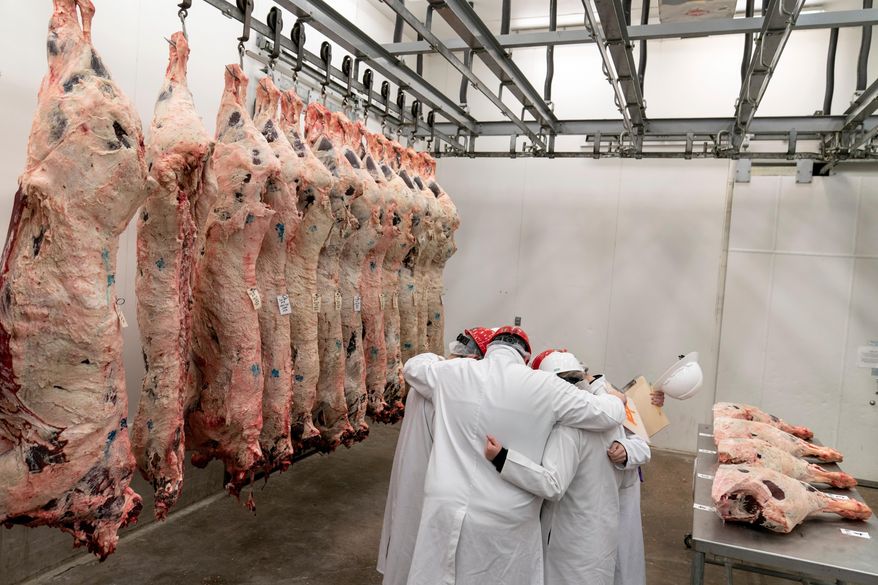 Team leader Kevin Eschberger, center, huddles his team in prayer next to half cows hanging in a freezer at the conclusion of a youth meat judging competition at Texas A&M University in College Station, Texas, on April 22, 2023. (AP Photo/David Goldman) **FILE**