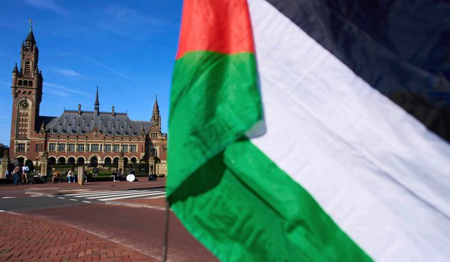 FILE -A Palestinian flag flies outside the International Court of Justice, rear, which opened hearings into a United Nations request for an advisory opinion on Israel's obligations to allow humanitarian assistance in Gaza and the West Bank, in The Hague, Netherlands, April 28, 2025. (AP Photo/Peter Dejong, File)