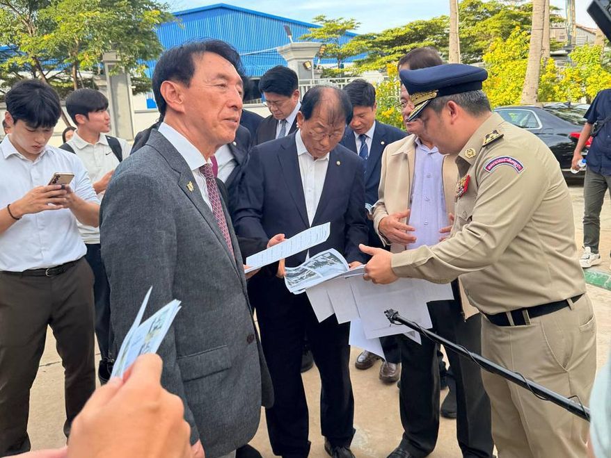 CORRECTS SOURCE - In this photo released by Secretariat of the Commission for Combating Online Scams (CCOS), South Korean lawmaker Kim Seok-Ki, front looks on as his delegation members look at some documents with a Cambodian police offer, right, as they visit a building complex that was allegedly used for online scam work, outside Phnom Penh, Cambodia, Wednesday, Oct. 22, 2025. (CCOS via AP)