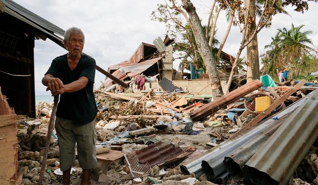 FILE -Bernardino Aspacio walks past rubbles from his damaged house due to Typhoon Rai in Alegria, Cebu province, central Philippines, Dec. 22, 2021. (AP Photo/Jay Labra, File)