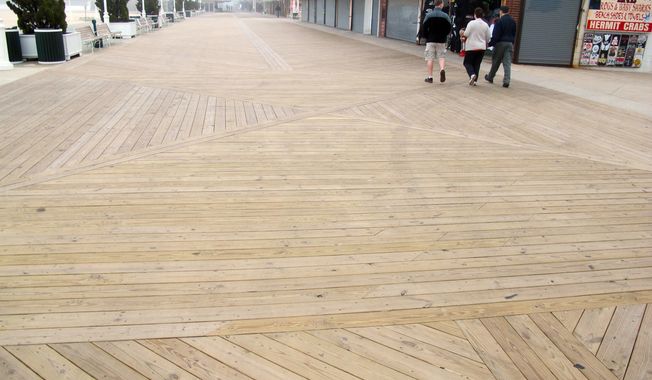 In this Monday, May 6, 2013 photo, people walk on the new boards of a nearly empty boardwalk on a cool, foggy day in Ocean City, Md. Local officials are optimistic they will see more visitors this summer after Memorial Day weekend kicks off the summer beach season. (AP Photo/Brian Witte)