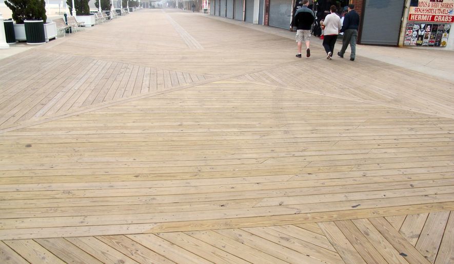In this Monday, May 6, 2013 photo, people walk on the new boards of a nearly empty boardwalk on a cool, foggy day in Ocean City, Md. Local officials are optimistic they will see more visitors this summer after Memorial Day weekend kicks off the summer beach season. (AP Photo/Brian Witte)