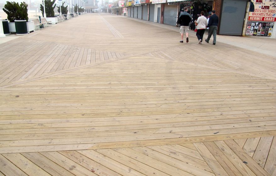 In this Monday, May 6, 2013 photo, people walk on the new boards of a nearly empty boardwalk on a cool, foggy day in Ocean City, Md. Local officials are optimistic they will see more visitors this summer after Memorial Day weekend kicks off the summer beach season. (AP Photo/Brian Witte)