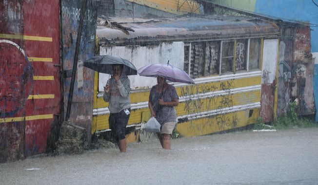 People wade through a street flooded by rains caused by Tropical Storm Melissa in Santo Domingo, Dominican Republic, Friday, Oct. 24, 2025. (AP Photo/Ricardo Hernandez)