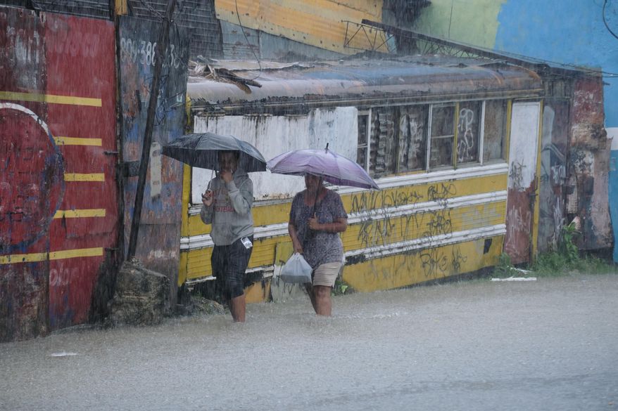 People wade through a street flooded by rains caused by Tropical Storm Melissa in Santo Domingo, Dominican Republic, Friday, Oct. 24, 2025. (AP Photo/Ricardo Hernandez)
