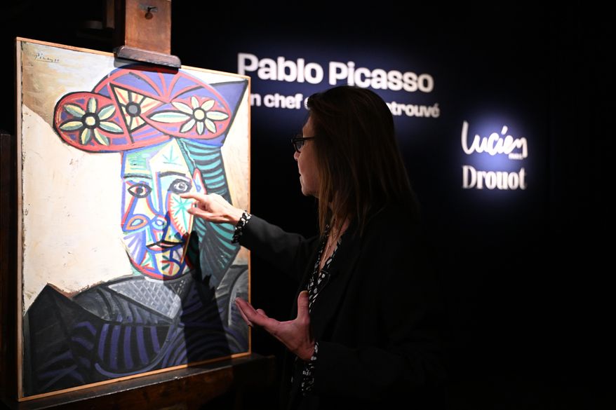 Art expert Agnes Sevestre-Barbe points to a rediscovered Picasso painting "Bust of a Woman in a Flowery Hat", Wednesday, Oct. 22, 2025 in Paris. The portrait painted in 1943 will be sold at auction Friday in Paris, was bought in 1944 and shows his partner Dora Maar. (AP Photo/Emma Da Silva)