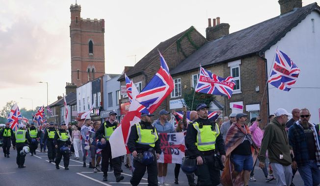 FILE - Police officers escort protesters near the Bell Hotel in Epping, London, Sunday, Aug. 31, 2025 after a temporary injunction that would have blocked asylum seekers from being housed at the hotel was overturned. (AP Photo/Alberto Pezzali, File)