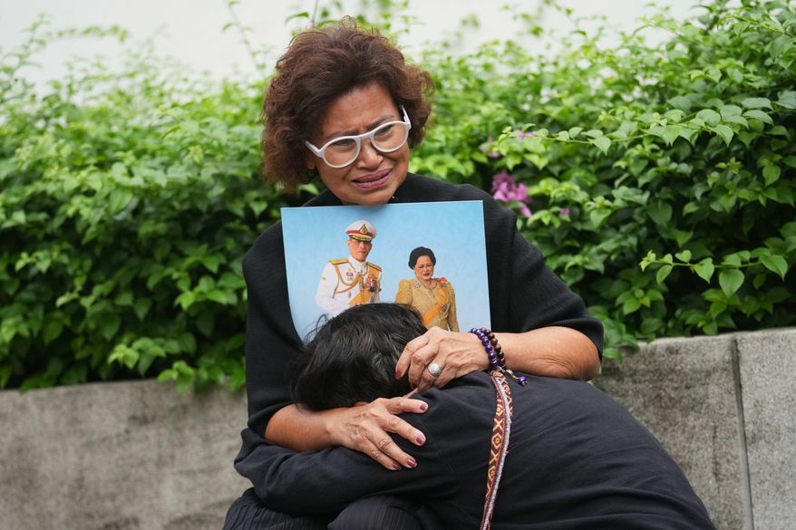 Thai people mourning as they hold the portrait of Thailand Queen Mother Sirikit in Bangkok, Thailand, Saturday, Oct. 25, 2025. (AP Photo/Sakchai Lalit)