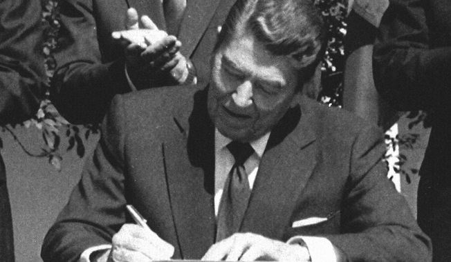 FILE - President Ronald Reagan signs legislation implementing the U.S.-Canada free trade agreement during a ceremony at the White House, Sept. 28, 1988. (AP Photo/Scott Stewart, File)