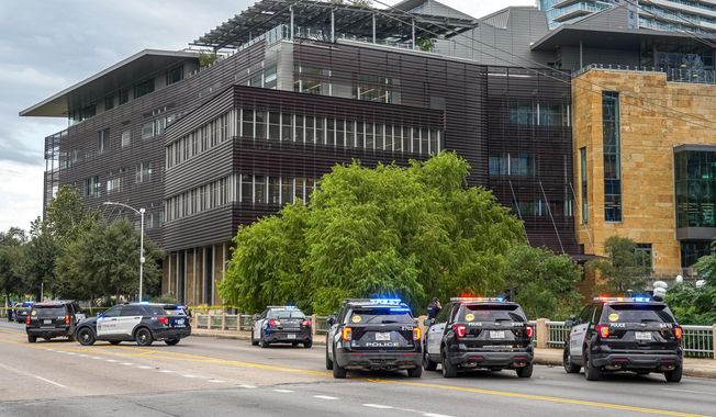 Police vehicles block the street after reports of a shooting at the Austin Public Library on César Chávez Street in downtown Austin, Texas on Saturday, Oct. 25, 2025. (Aaron E. Martinez/Austin American-Statesman via AP)