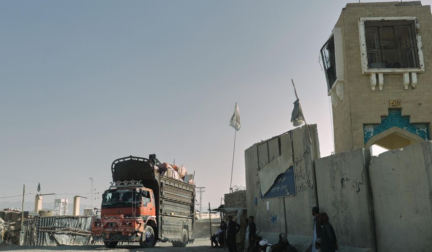 People wait near the closed gate at the Spin Boldak border crossing with Pakistan, after the border was shut for nearly two weeks following clashes between Afghan and Pakistani forces, in Kandahar province, Afghanistan, Thursday, Oct. 23, 2025. (AP Photo/Sibghatullah)