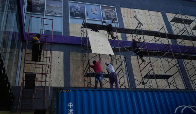 Workers board up shop windows ahead of Hurricane Melissa's forecast arrival in Kingston, Jamaica, Sunday, Oct. 26, 2025. (AP Photo/Matias Delacroix)