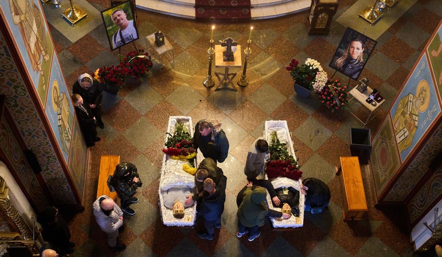 Relatives, colleagues and friends of two Ukrainian 43-year-old journalists Olena Hubanova, who worked under the pseudonym Alyona Gramova, and cameraman Yevhen Karmazin, who were killed on Thursday, Oct. 23, mourn over their coffins during a funeral service at St. Michael Monastery in Kyiv, Ukraine, Monday, Oct. 27, 2025. (AP Photo/Efrem Lukatsky)