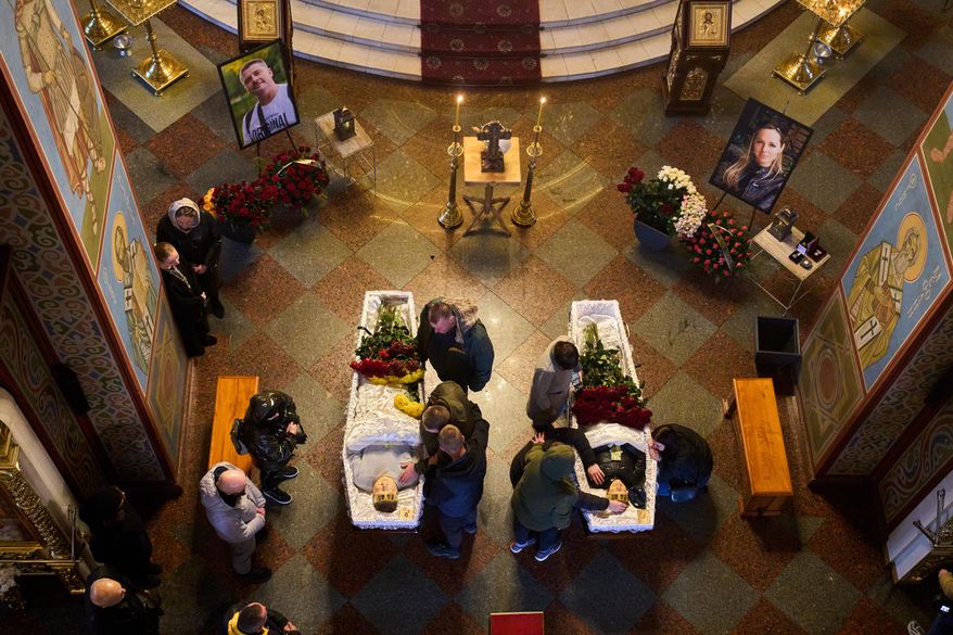 Relatives, colleagues and friends of two Ukrainian 43-year-old journalists Olena Hubanova, who worked under the pseudonym Alyona Gramova, and cameraman Yevhen Karmazin, who were killed on Thursday, Oct. 23, mourn over their coffins during a funeral service at St. Michael Monastery in Kyiv, Ukraine, Monday, Oct. 27, 2025. (AP Photo/Efrem Lukatsky)