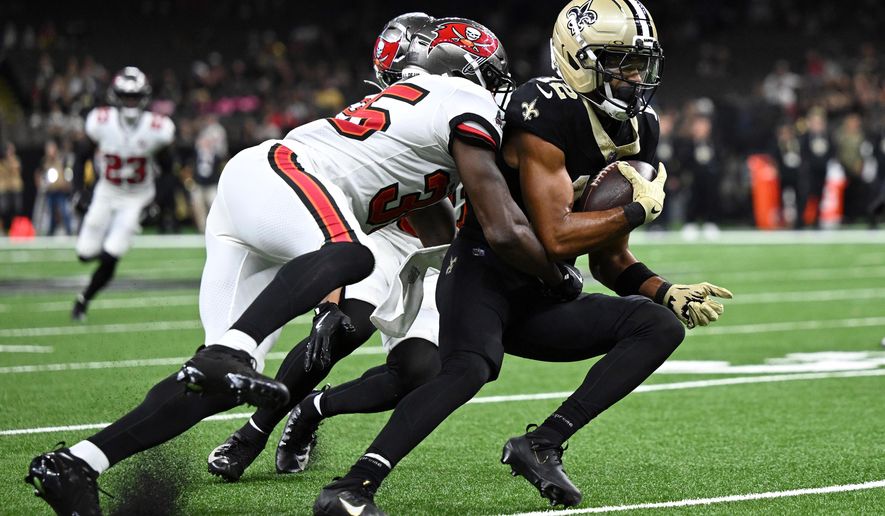New Orleans Saints wide receiver Chris Olave (12) is stopped by Tampa Bay Buccaneers cornerback Jamel Dean (35) and safety Antoine Winfield Jr. during the second half of an NFL football game Sunday, Oct. 26, 2025, in New Orleans. (AP Photo/Ella Hall)