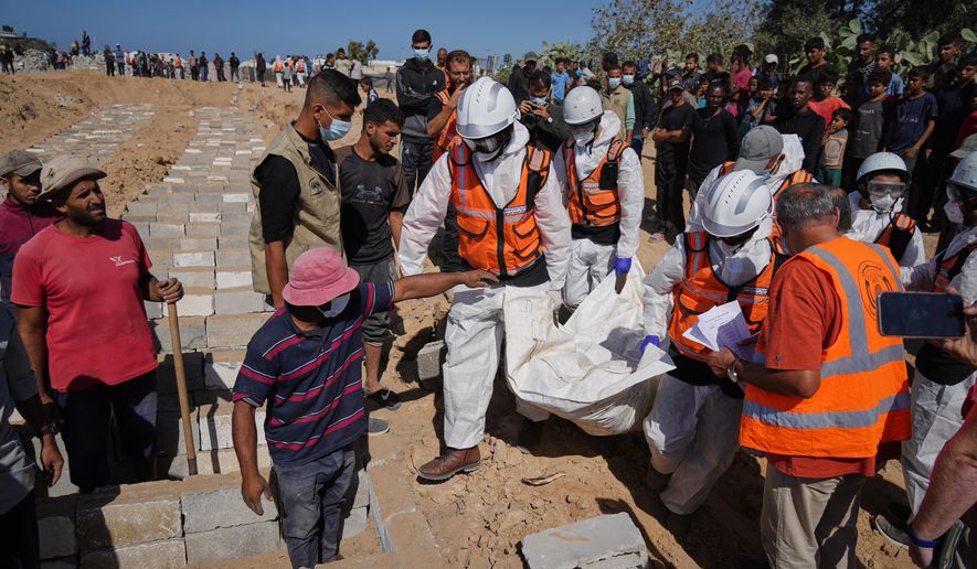 Bodies of unidentified Palestinians returned from Israel are buried in a mass grave in Deir al-Balah, Gaza Strip, Monday, Oct. 27, 2025. (AP Photo/Jehad Alshrafi)