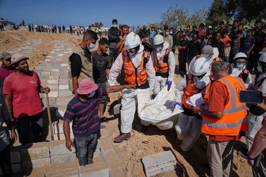 Bodies of unidentified Palestinians returned from Israel are buried in a mass grave in Deir al-Balah, Gaza Strip, Monday, Oct. 27, 2025. (AP Photo/Jehad Alshrafi)