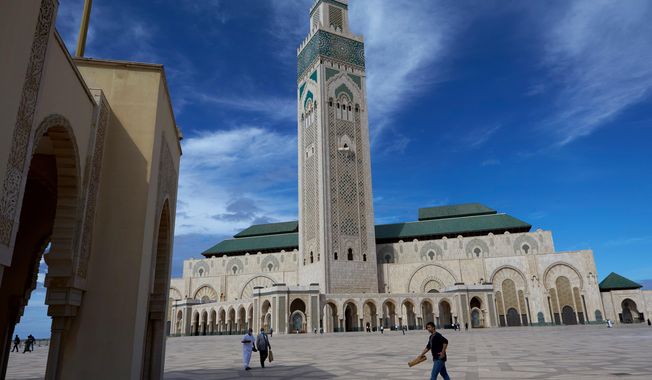 FILE - People walk past the great Hassan II Mosque in Casablanca, Morocco, Oct. 16, 2020. (AP Photo/Abdeljalil Bounhar, File)