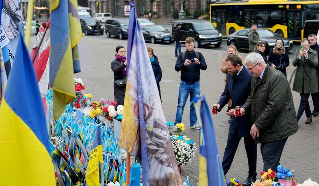Ukraine's Foreign Minister Andrii Sybiha and Estonia's Minister of Foreign Affairs Margus Tsahkna place candles at a memorial for fallen Ukrainian soldiers in Independence Square, Monday, Oct. 27, 2025, in Kyiv, Ukraine. (AP Photo/Julia Demaree Nikhinson)