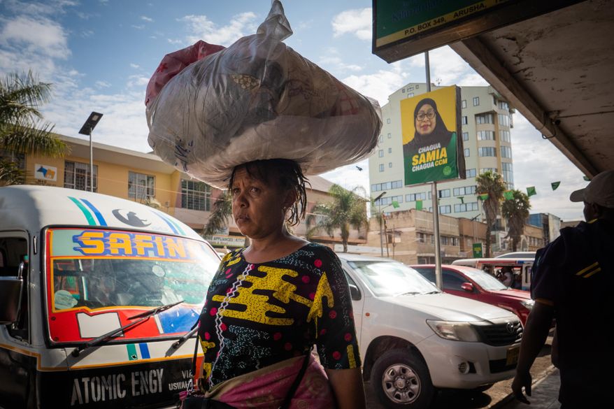 Pedestrians walk past a billboard for Tanzanian presidential candidate Samia Suluhu Hassan, of the ruling Chama Cha Mapinduzi party, in Arusha, Tanzania, Oct. 8, 2025. (AP Photo)