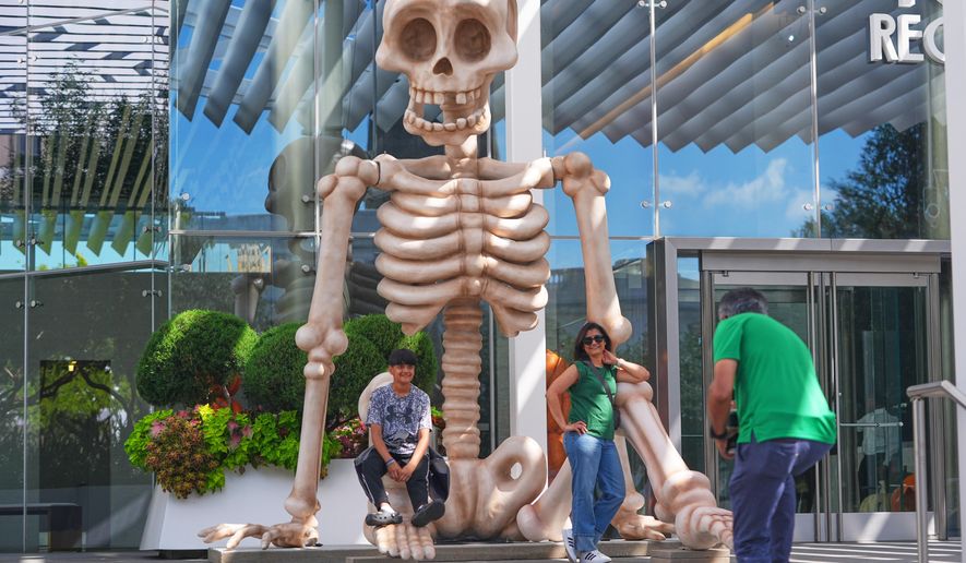 Sam Desai, right, takes a Halloween-themed photo of his wife, Sonia Desai, and son, Rishan Desai, in downtown Dallas, Sept. 27, 2025. (AP Photo/LM Otero, File)