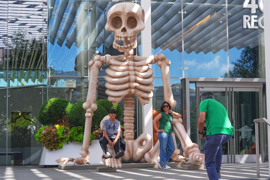 Sam Desai, right, takes a Halloween-themed photo of his wife, Sonia Desai, and son, Rishan Desai, in downtown Dallas, Sept. 27, 2025. (AP Photo/LM Otero, File)