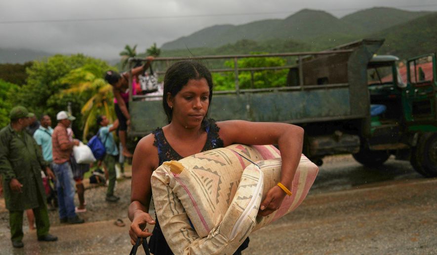 A woman carrying a mattress in the rain evacuates before the arrival of Hurricane Melissa in Cañizo, a community in Santiago de Cuba, Tuesday, Oct. 28, 2025. (AP Photo/Ramón Espinosa)
