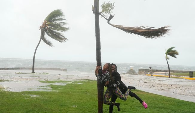 A couple jokes around on the coast in Kingston, Jamaica, as Hurricane Melissa approaches, Tuesday, Oct. 28, 2025. (AP Photo/Matias Delacroix)