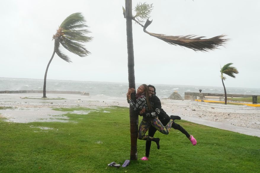 A couple jokes around on the coast in Kingston, Jamaica, as Hurricane Melissa approaches, Tuesday, Oct. 28, 2025. (AP Photo/Matias Delacroix)