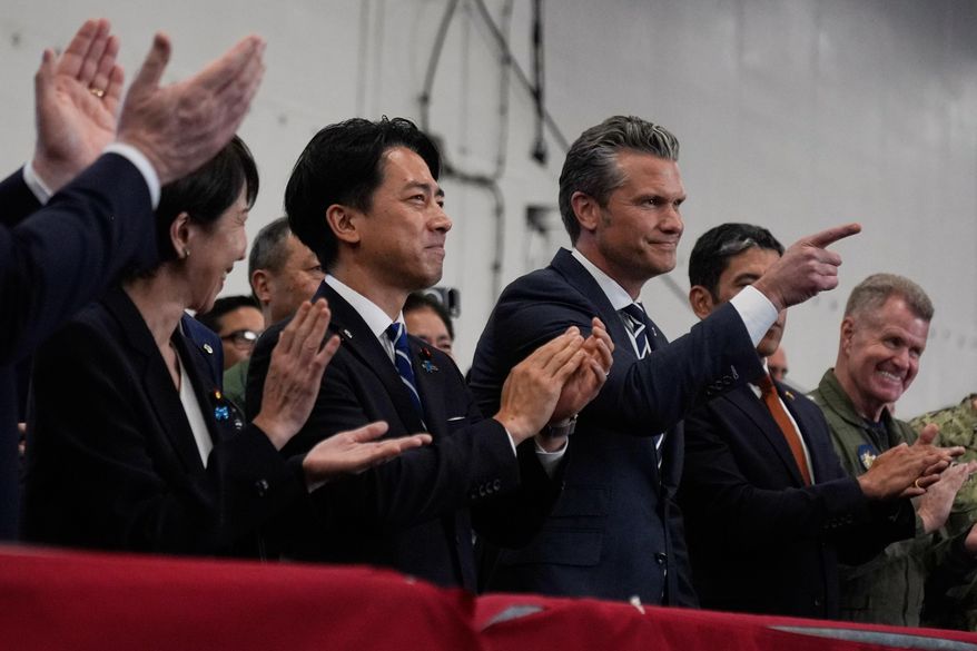 U.S. Defense Secretary Pete Hegseth, center right, with Japanese Prime Minister Sanae Takaichi, left, and Defense Minister Shinjiro Koizumi, gestures as they listen to President Donald Trump speak to members of the military aboard the USS George Washington, an aircraft carrier docked at an American naval base, in Yokosuka, south of Tokyo, Tuesday, Oct. 28, 2025. (AP Photo/Mark Schiefelbein)