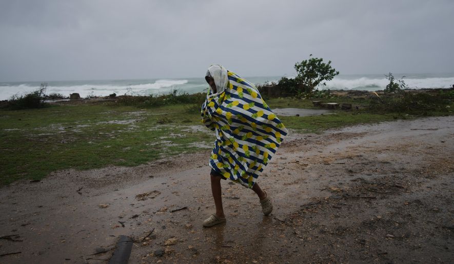 A man walks in the rain before the arrival of Hurricane Melissa in Canizo, a village in Santiago de Cuba, Tuesday, Oct. 28, 2025. (AP Photo/Ramón Espinosa)