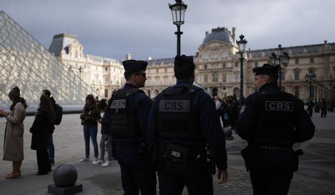Riot police officers patrol as people queue to enter Le Louvre museum Monday, Oct. 27, 2025 in Paris. (AP Photo/Christophe Ena)