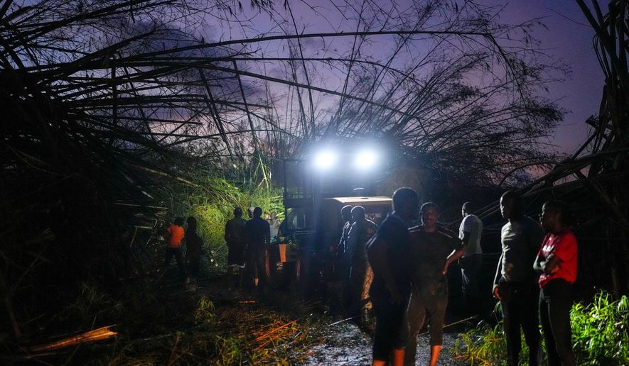 Workers clear downed trees and debris to make way for a convoy carrying aid to Black River, which was hit by Hurricane Melissa, as it moves through Holland Bamboo, Jamaica, Wednesday, Oct. 29, 2025. (AP Photo/Matias Delacroix)
