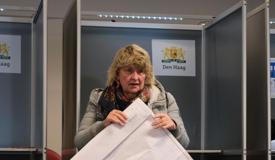 A woman holds a sheet of candidates as she prepares to vote at a polling station during general elections in The Hague, Netherlands, Wednesday, Oct. 29, 2025. (AP Photo/Patrick Post)