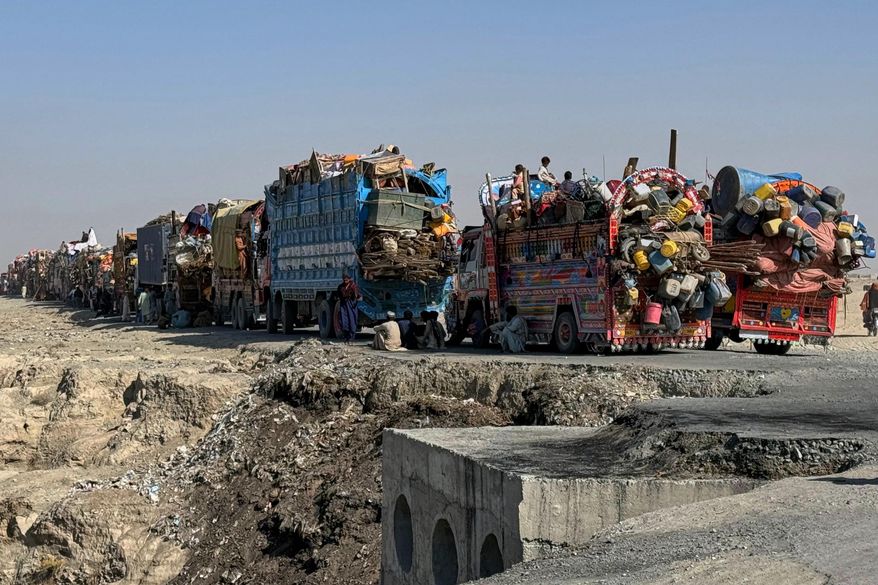 Afghan refugees sit beside trucks loaded with their belongings as they wait their turn to leave for their homeland through a border crossing point which partially opens following Oct.19 ceasefire, on the outskirts of Chaman, a border town on the Pakistan Afghan border, Wednesday, Oct. 29, 2025. (AP Photo/H. Achakzai)