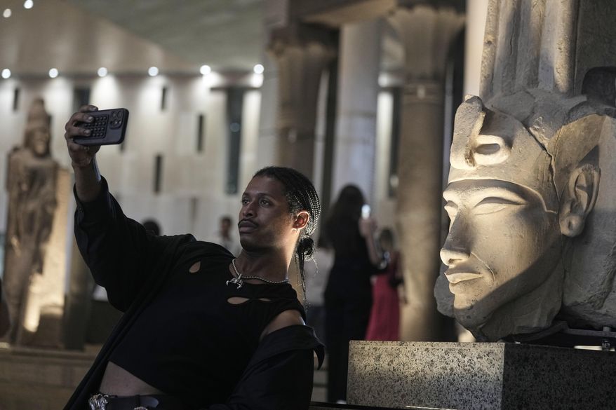 A tourist takes a selfie in front of Akhenaten statue during his visit to the Grand Egyptian Museum in Giza, Egypt, Friday, May 23, 2025. (AP Photo/Amr Nabil)