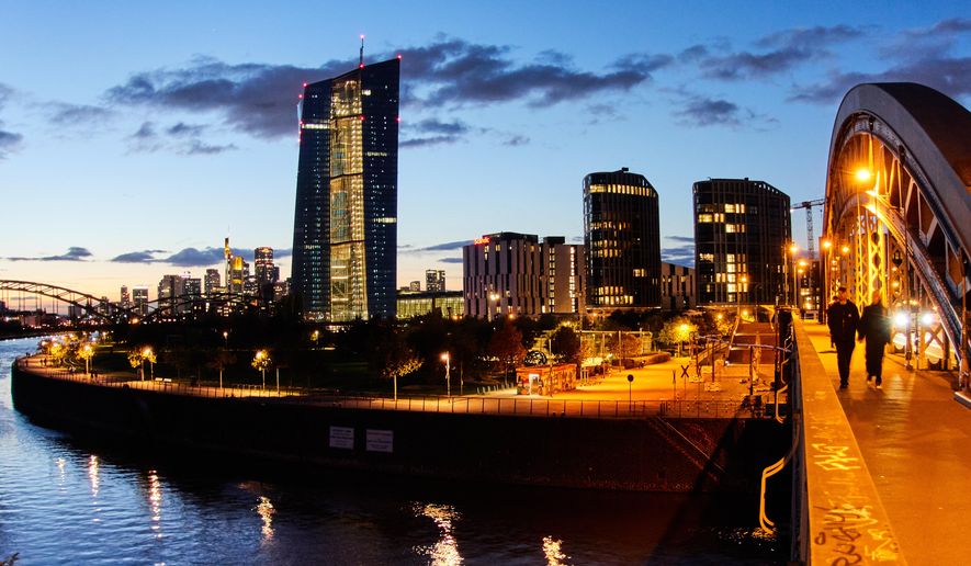 People walk over a bridge near the European Central Bank in Frankfurt, Germany, Sunday, Oct. 26, 2025. (AP Photo/Michael Probst)