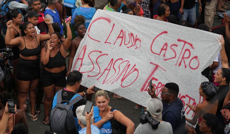 Protesters display a banner reading in Portuguese "Claudio Castro Murderer," referring to Rio de Janeiro state Governor Claudio Castro, a day after a deadly police raid targeting the Comando Vermelho gang in the Complexo da Penha favela of Rio de Janeiro, Brazil, Wednesday, Oct. 29, 2025. (AP Photo/Silvia Izquierdo)