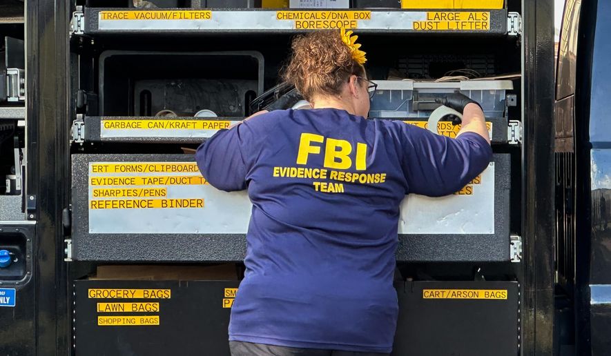 An FBI agent stands by an Evidence Response Team truck outside a home in a Dearborn, Mich., neighborhood on Friday, Oct. 31, 2025. (AP Photo/Mike Householder)
