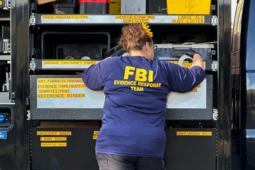 An FBI agent stands by an Evidence Response Team truck outside a home in a Dearborn, Mich., neighborhood on Friday, Oct. 31, 2025. (AP Photo/Mike Householder)