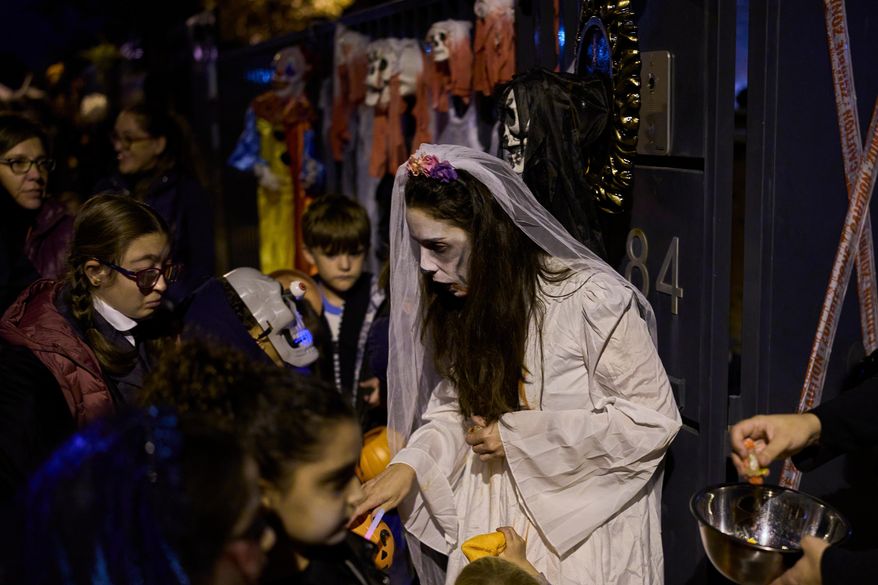 People dressed in scary costumes take part in a Halloween celebration that gives sweets to children in Paracuellos del Jarama, Spain, Friday, Oct. 31, 2025. (AP Photo/Manu Fernandez)