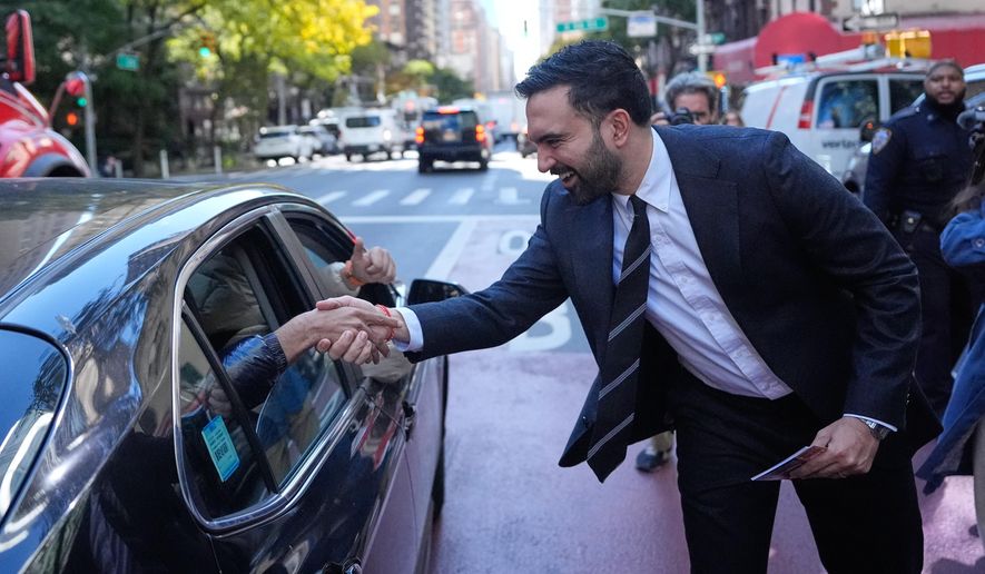 New York City mayoral candidate Zohran Mamdani greets some people in a car while surrounded by reporters in New York, Monday, Oct. 27, 2025. (AP Photo/Seth Wenig)