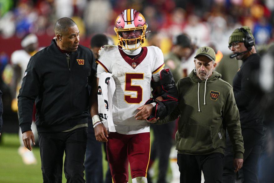Washington Commanders quarterback Jayden Daniels (5) is helped off the field after injuring his arm in the second half of an NFL football game against the Seattle Seahawks, Sunday, Nov. 2, 2025, in Landover, Md. (AP Photo/Nick Wass)
