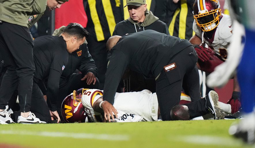 Washington Commanders quarterback Jayden Daniels (5) lays on the ground and is attended to by members of the Washington Commanders medical team after injuring his arm during the second half of an NFL football game, Sunday, Nov. 2, 2025, in Landover, Md. (AP Photo/Stephanie Scarbrough)