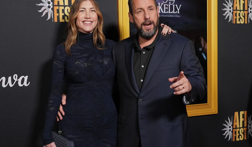 Adam Sandler, right, a cast member in "Jay Kelly," arrives with his wife Jackie Sandler at the AFI Fest premiere of the film on Thursday, Oct. 23, 2025, at TCL Chinese Theatre in Los Angeles. (AP Photo/Chris Pizzello)