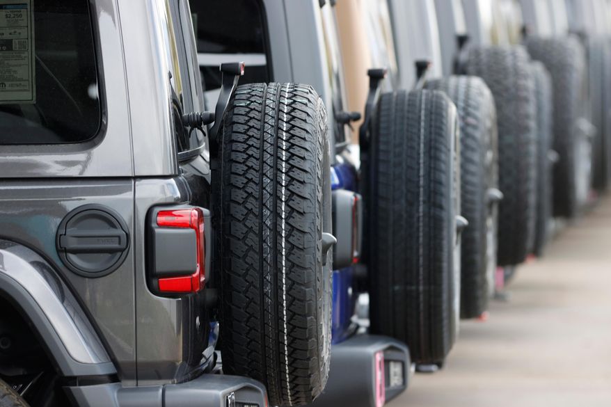 FILE - Spare tires are seen on a long row of unsold 2020 Wranglers sit at a Jeep dealership in Englewood, Colo., on April 26, 2020. (AP Photo/David Zalubowski, File)